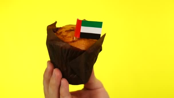 Cupcake met vlag Verenigde Arabische Emiraten op mannelijke palm tegen gele achtergrond — Stockvideo