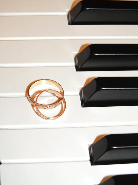 Two gold wedding rings on piano — Stock Photo, Image