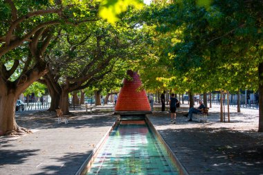Şehir Vaha 'sı Kırmızı Heykeli ve Yansıyan Havuzu olan bir park