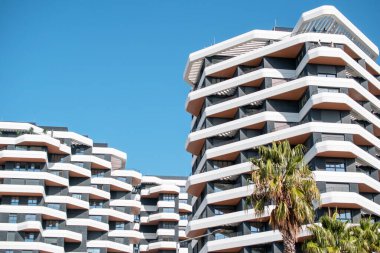 Mavi gökyüzüne karşı balkonları olan modern bir apartman.  