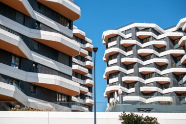 Arka planda palmiye ağaçları ve mavi gökyüzü olan modern apartman binası.