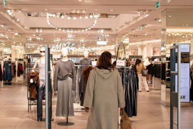 Parlak bir perakende mağazasında kıyafet karıştıran bir kadın.