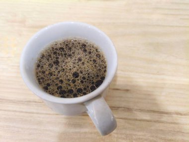 Ahşap masasında köpüklü sade kahvenin yukarıdan görünüşü