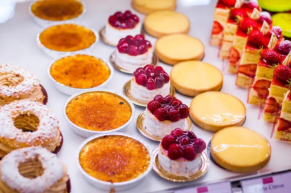 Pastry shop with variety of donuts, Creme brulee, cakes with fruits and berries — Stock Photo, Image