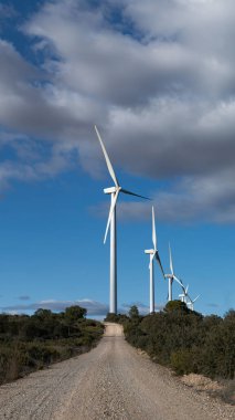 Kırsal Toprak Yol Yokuş yukarı Beyaz Rüzgar Türbinleri 'nin Bulutlu Mavi Gökyüzü Altında