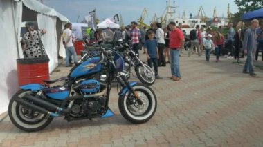 Odessa, Ukrayna - 11 Haziran 2016: Bike Cars ve Rock n Roll retro festivali. Vintage motosiklet yakınından geçen insanlar.