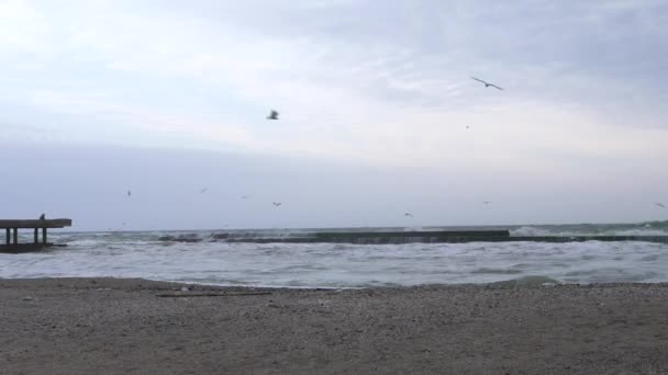 Eenzame man zit op hoge betonnen pier tijdens een enorme storm. Golven die breken op pier. — Stockvideo