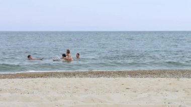Yüzme ve deniz kumlu plaja yakın turkuaz oynayan genç insanlar.