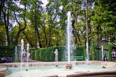 Parkın ortasında mavi gökyüzünün altında eski bir çeşme var. 