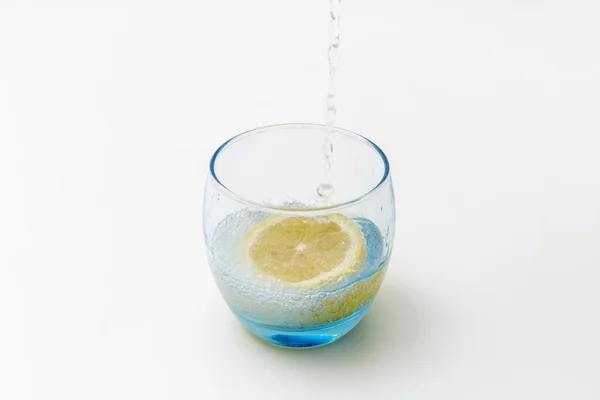 Verre d'eau rafraîchissante avec éclaboussures de citron isolé sur du blanc — Photo