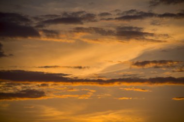 Güneş batıyor, bulutlar turuncu ve altın renginde.