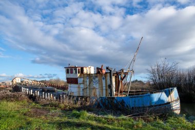 Çürüyen ahşap güverteleri olan eski bir tekne yoksunluk, çürüme ve başarısızlığın resmini çiziyor. Denizcilik ve Denizcilik.