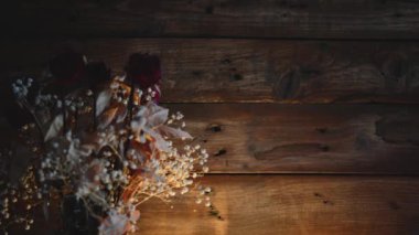 Bir demet kuru gül ve parlayan ışıklar ahşap bir arka planda