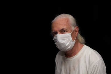 Siyah arka planda beyaz saçlı, yaşlı bir adam..