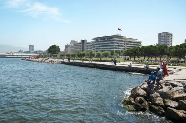Türkiye, İzmir - 2 Temmuz 2021 Kayalıklarda ve İzmir kentinde balık tutan erkekler