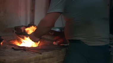 Atölyesindeki yaşlı adam bakır kaseyi tenekeyle kaplıyor. Kalaycı bakır nesneyi alevlerle kaplıyor.