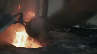 Atölyesindeki yaşlı adam bakır kaseyi tenekeyle kaplıyor. Kalaycı bakır nesneyi alevlerle kaplıyor.