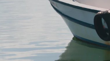 Ticarete hazır deniz görüntüleri, titreyen yansımalarla sakin sularda dinlenen bir balıkçı teknesi gösteriyor. Aşağı eğimli kamera hareketi dokuyu ve dinginliği vurgular. Kıyı yaşam tarzı, seyahat, deniz sanayii ve sükunet temaları için ideal.