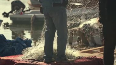 Balıkçılar balıkçılıktan sonra liman limanında ağ topluyor. Balıkçıların denizden döndükten sonra balıkçı ağlarıyla balık avladıklarını gösteren ticari görüntüler. Otantik ışık ve doğal iş akışıyla gerçek koşullarda çekildi, yapay zekayla değil..