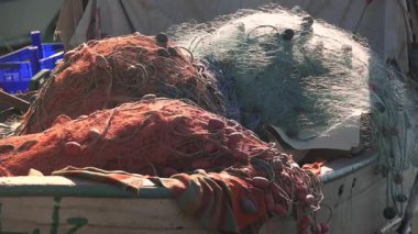 Yat limanına demirlenmiş geleneksel ahşap balıkçı teknesine istiflenmiş balık ağları. Ticari deniz ürünleri üretimi ve kıyı balıkçılık endüstrisi kavramı.