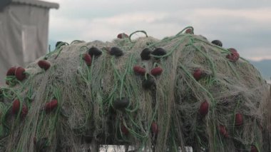 Deniz kenarındaki ahşap bir iskeleye istiflenmiş balık ağlarının otantik görüntüleri. Geleneksel kıyı geçimini yansıtan detaylı deniz ekipmanı sahnesi. Gerçek çekim, yapay zeka değil..
