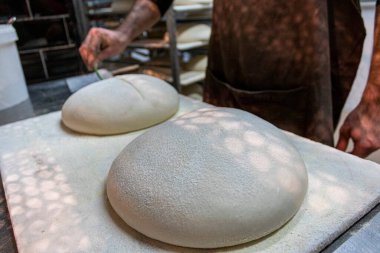 Beyaz bir adamın eline yakın çekim. Çiğ ekmek kesiyor.