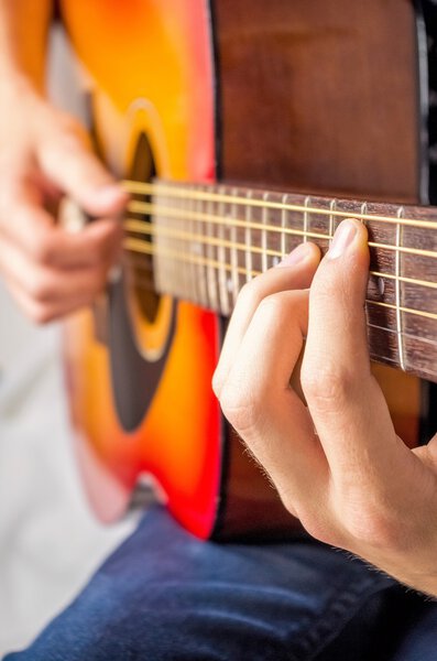 Male hands playing acoustic guitar, close up