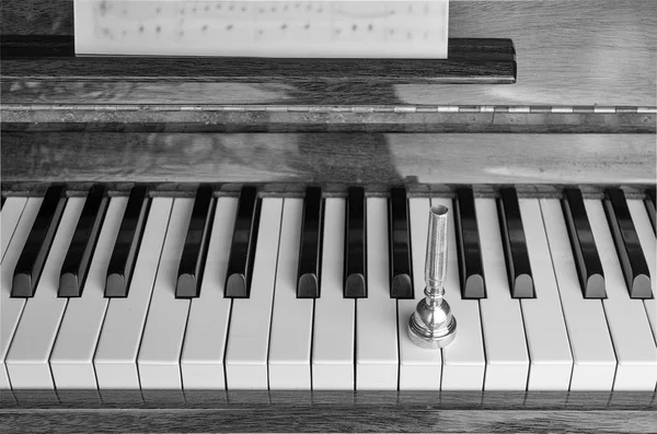 Um bocal de trompete sobre as teclas de piano, de perto — Fotografia de Stock
