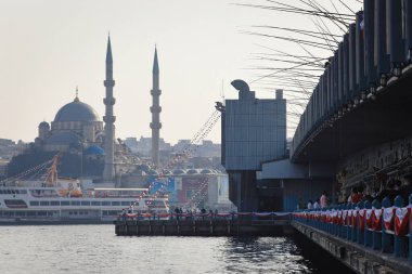 İSTANBUL, Turkey - 06 Ekim 2020. Altın Boynuz 'daki Galata Köprüsü' nün arkasında Valide Sultan Camii var. Köprüye monte edilmiş pek çok oltanın görüntüsü. İstanbul, Türkiye.