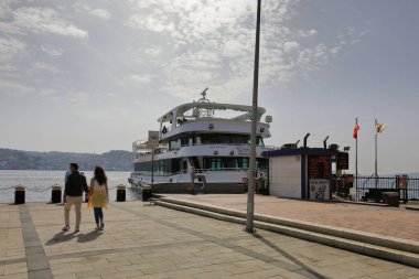 İSTANBUL, Turkey - 06 Ekim 2020. Rıhtıma demirlemiş yolcu gemisinin önündeki genç çift. Ortakoy rıhtım meydanından görüntü. Beşiktaş ilçesi, İstanbul kenti, Türkiye.