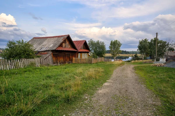 Village street in summer. Old wooden house with barn. Ancient village of Visim, Sverdlovsk region, Urals, Russia.