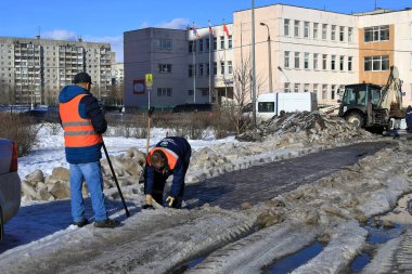 BALASHIKHA, Rusya- 19 Mart 2021. Belediyenin iki çalışanı buzdan yolu temizliyor. Okul manzarası N 27. Balashikha şehri, Moskova bölgesi, Rusya.