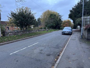 Thurcaston, Leicestershire, UK November 9th 2025 Quiet Urban Street With Brick Buildings, Sidewalk, and Green Hedge Near Residential Houses