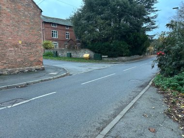 Thurcaston, Leicestershire, UK November 9th 2025 Quiet Urban Street With Brick Buildings, Sidewalk, and Green Hedge Near Residential Houses
