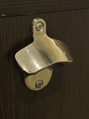 Görünür vidayla Koyu Ahşap Kapıdaki Metal Şişe Açacağının Yakın Çekimi