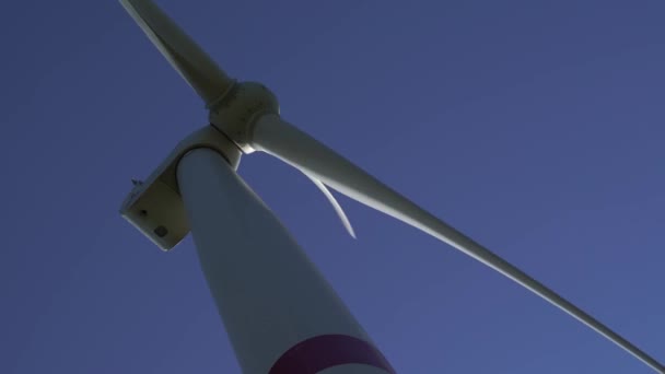 Bladen van een grote windturbine in een veld tegen een achtergrond van troebele blauwe lucht. Alternatieve energiebronnen. Winderig park. Ecologische energie.Industrieel — Stockvideo