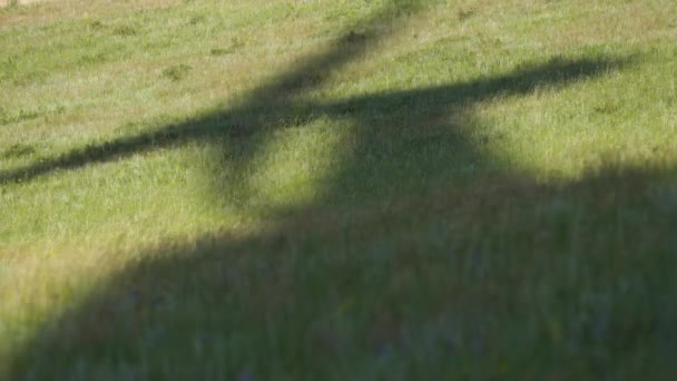 Schaduw van bladen van een grote windturbine in een veld met groen gras. Alternatieve energiebronnen. Winderig park. Ecologische energie. — Stockvideo