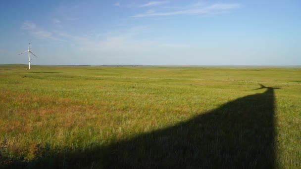 緑の芝生のフィールドに大きな風力タービンのブレードの影。代替エネルギー源。ウィンディ・パーク。生態エネルギー. — ストック動画