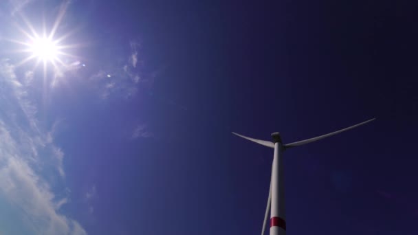 Ufukta bulutlu mavi gökyüzü ve güzel tepeleri olan bir tarladaki büyük bir rüzgar türbininin bıçakları. Alternatif enerji kaynakları. Rüzgarlı park. Ekolojik enerji. Sanayi. — Stok video