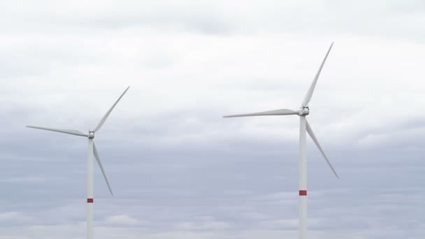 Movimiento de las palas de un gran aerogenerador en un campo sobre un fondo de cielo gris nublado en el horizonte con una hermosa colinas. Fuentes de energía alternativas. Parque de viento. Energía ecológica.Industrial — Vídeo de stock