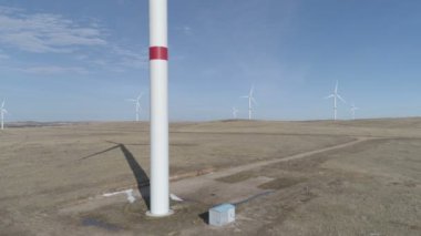 Ufukta bulutlu mavi gökyüzü ve güzel tepeleri olan bir tarladaki büyük bir rüzgar türbininin bıçakları. Alternatif enerji kaynakları. Rüzgarlı park. Ekolojik enerji. Sanayi.