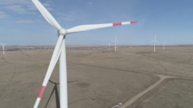 Ufukta bulutlu mavi gökyüzü ve güzel tepeleri olan bir tarladaki büyük bir rüzgar türbininin bıçakları. Alternatif enerji kaynakları. Rüzgarlı park. Ekolojik enerji. Sanayi.