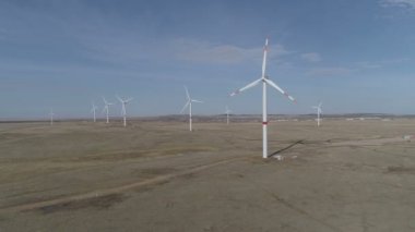 Ufukta bulutlu mavi gökyüzü ve güzel tepeleri olan bir tarladaki büyük bir rüzgar türbininin bıçakları. Alternatif enerji kaynakları. Rüzgarlı park. Ekolojik enerji. Sanayi.