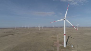 Ufukta bulutlu mavi gökyüzü ve güzel tepeleri olan bir tarladaki büyük bir rüzgar türbininin bıçakları. Alternatif enerji kaynakları. Rüzgarlı park. Ekolojik enerji. Sanayi.