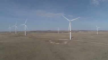 Ufukta bulutlu mavi gökyüzü ve güzel tepeleri olan bir tarladaki büyük bir rüzgar türbininin bıçakları. Alternatif enerji kaynakları. Rüzgarlı park. Ekolojik enerji. Sanayi.