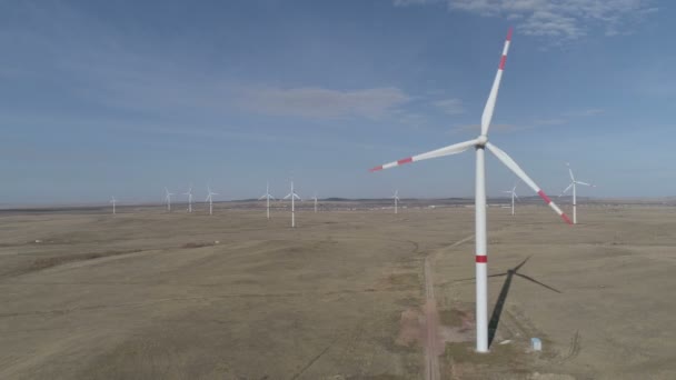 Blades of a large wind turbine in a field against a background of cloudy blue sky on the horizon with a beautiful hills. Alternative energy sources. Windy park. Ecological energy.Industrial — Stock Video