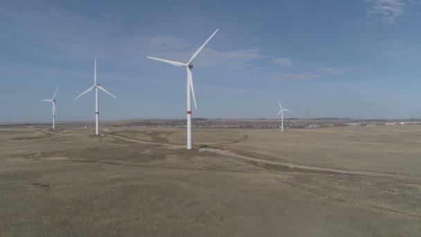 Hojas de un gran aerogenerador en un campo sobre un fondo de cielo azul nublado en el horizonte con unas hermosas colinas. Fuentes de energía alternativas. Parque de viento. Energía ecológica.Industrial — Vídeo de stock