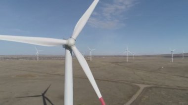 Ufukta bulutlu mavi gökyüzü ve güzel tepeleri olan bir tarladaki büyük bir rüzgar türbininin bıçakları. Alternatif enerji kaynakları. Rüzgarlı park. Ekolojik enerji. Sanayi.