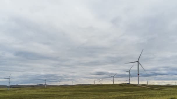 Blad av en stor vindkraftverk i ett fält mot en bakgrund av molnigt blå himmel på horisonten med en vacker kullar. Alternativa energikällor. Blåsig park. Ekologisk energi.Industriell — Stockvideo