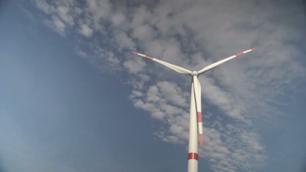 Lâminas de uma grande turbina eólica em um campo contra um fundo de céu azul nublado no horizonte com belas colinas. Fontes de energia alternativas. Parque ventoso. Energia ecológica.Industrial — Vídeo de Stock